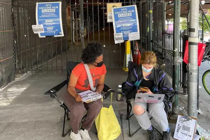 Mutual aid group volunteers sit outside the shuttered Bushwick Educational Campus to help direct people who show up to the new site.